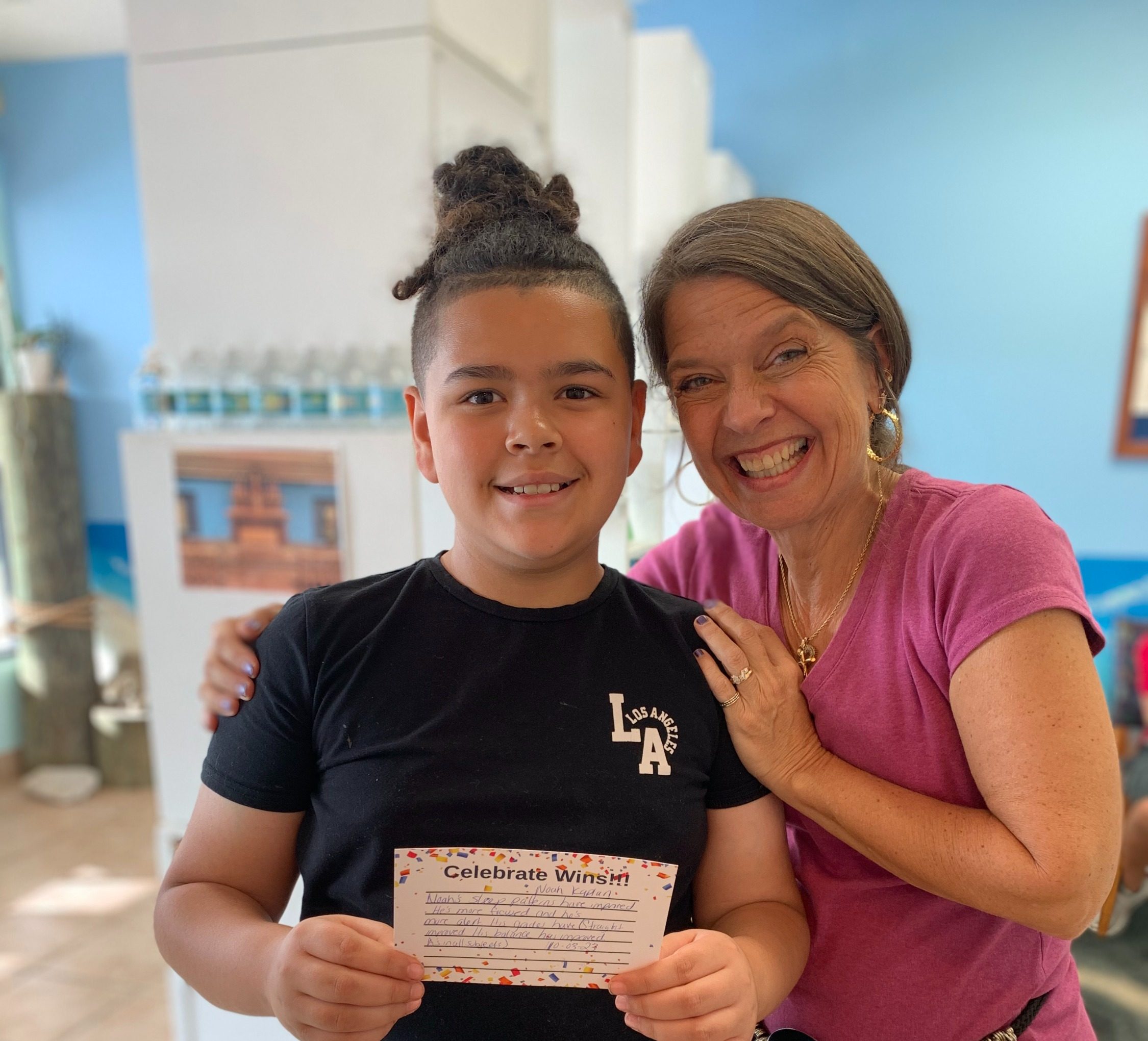 Boy holding a Celebrate Wins card beside Dr. Karolyn