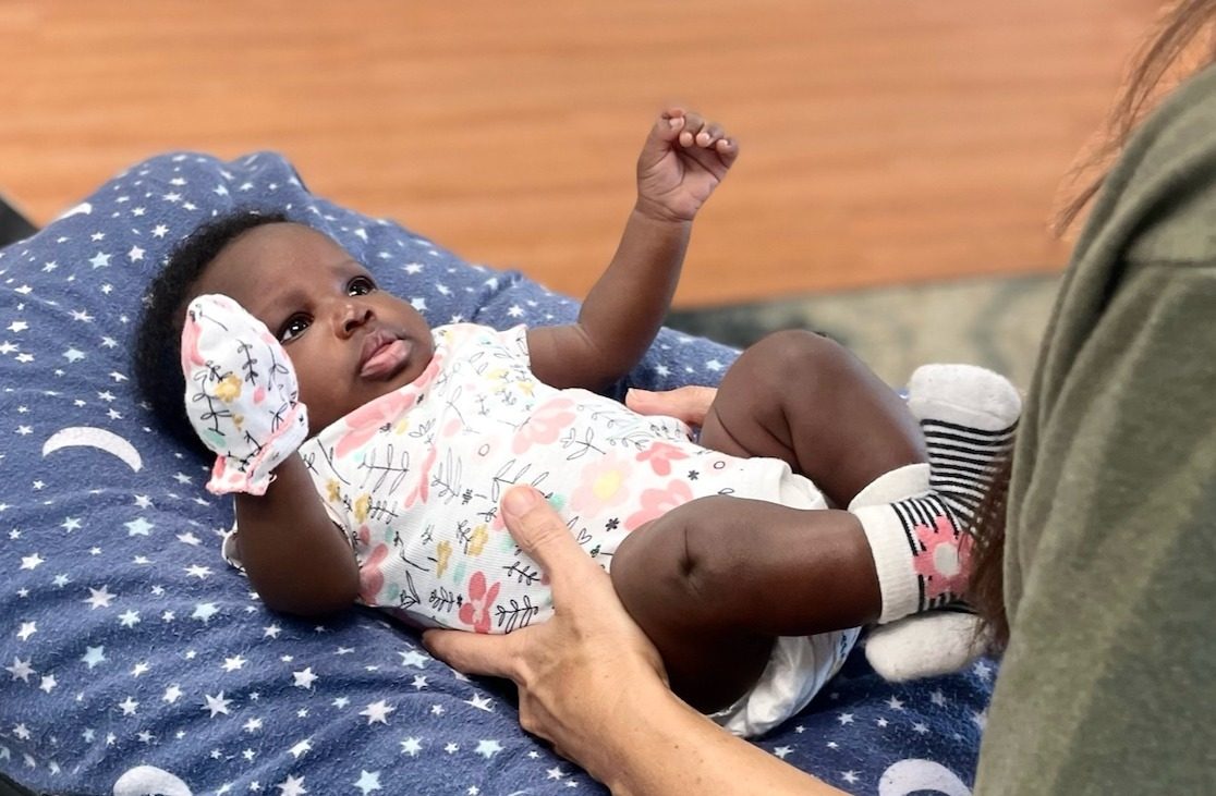 Infant lying on a moon-and-stars blanket during a pediatric visit