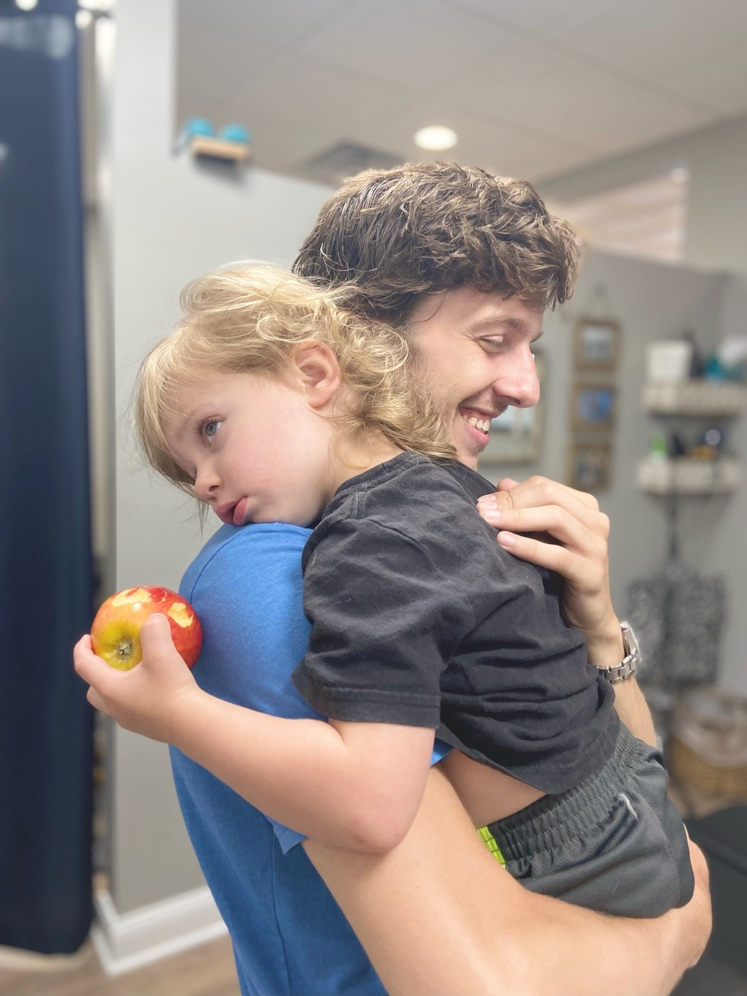 Father hugging a young child holding an apple