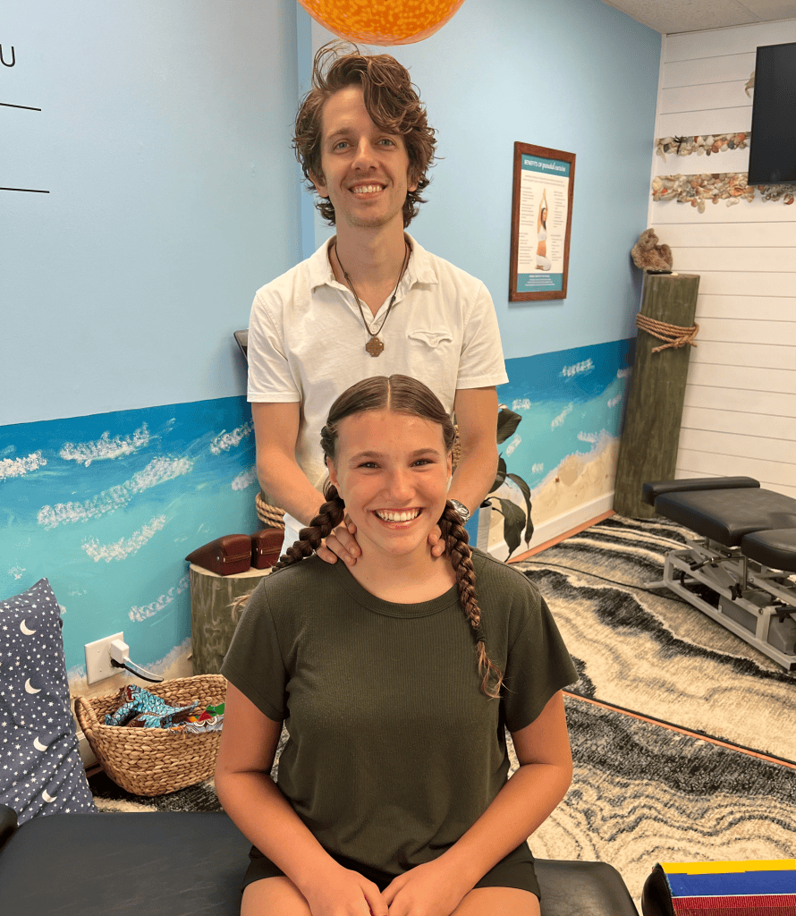 Young practitioner standing behind a smiling girl in the office