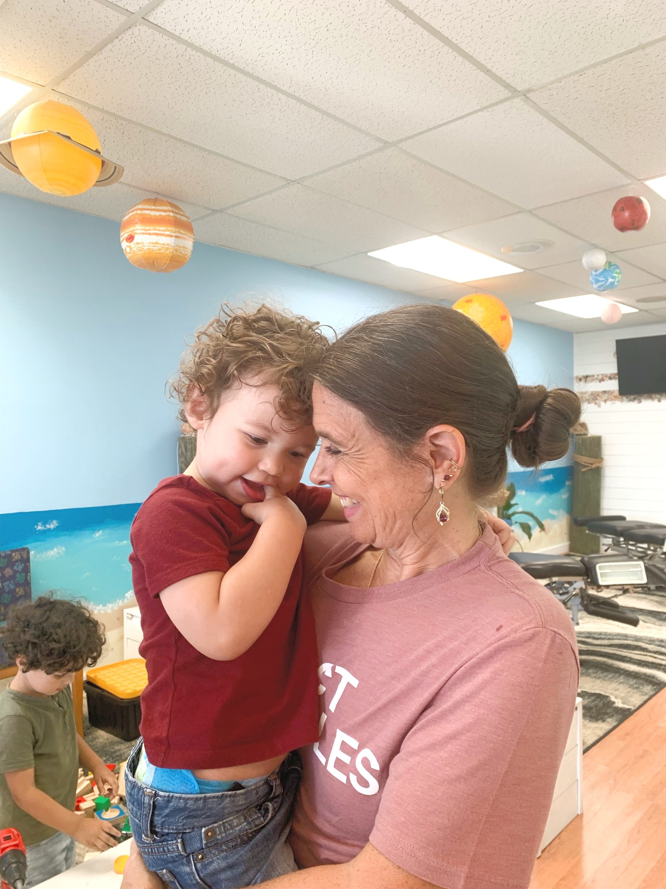 Dr. Karolyn holding a smiling toddler under hanging planet decorations