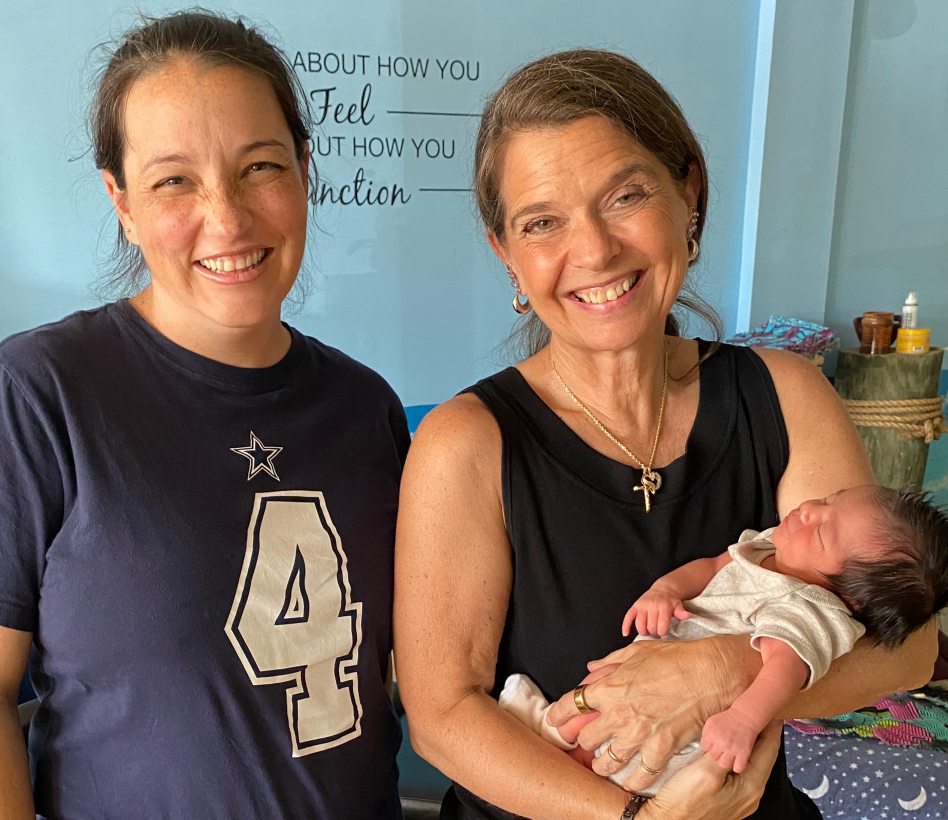 Dr. Karolyn holding a newborn while standing with the baby's mother