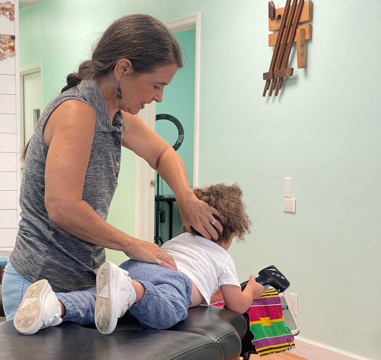 Dr. Karolyn cradling a child's neck during an adjustment on a table