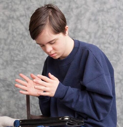 Teenager looking at their hands beside a tablet device