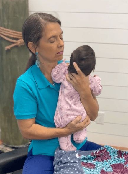 Woman in a turquoise shirt holding a newborn baby in the office