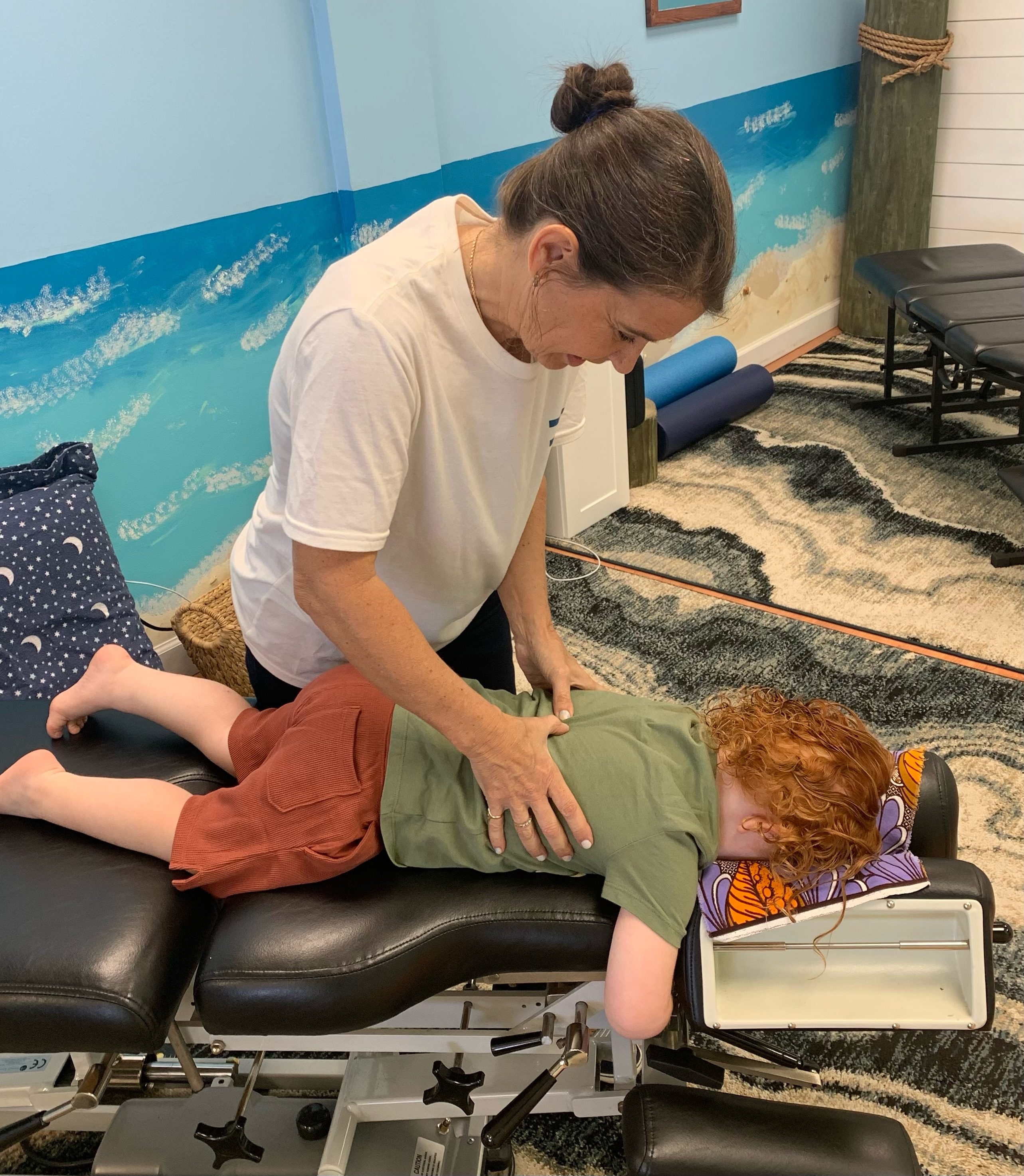Dr. Karolyn adjusting a red-haired child on a chiropractic table