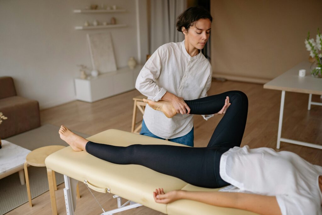Practitioner supporting a patient's bent leg on a treatment table