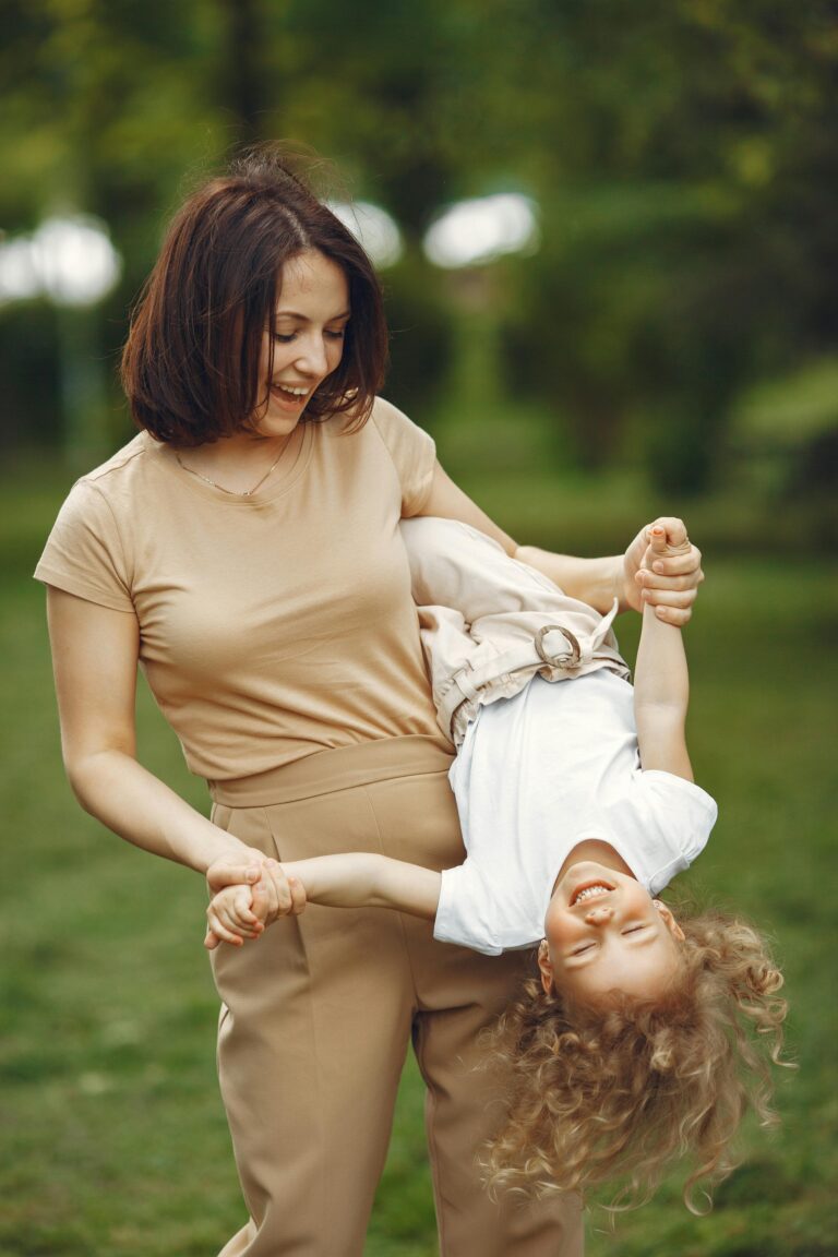 Mother holding her smiling daughter upside down outdoors