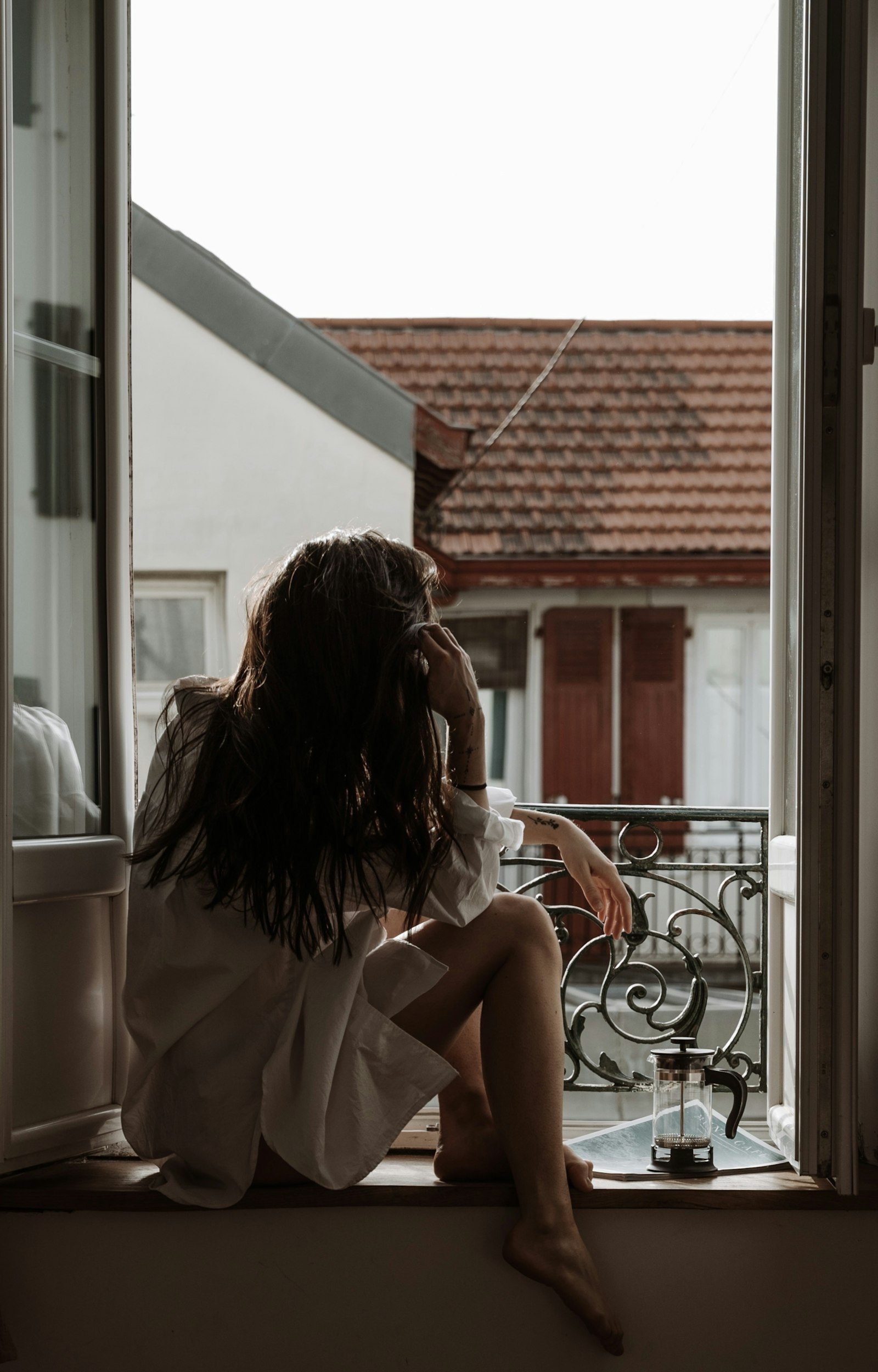 Woman sitting on a window sill in soft daylight