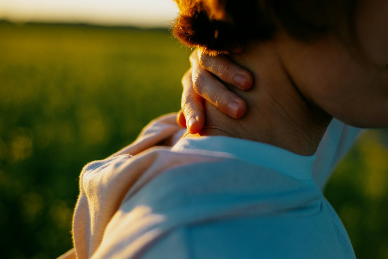 Woman standing in a field with her hands on her neck