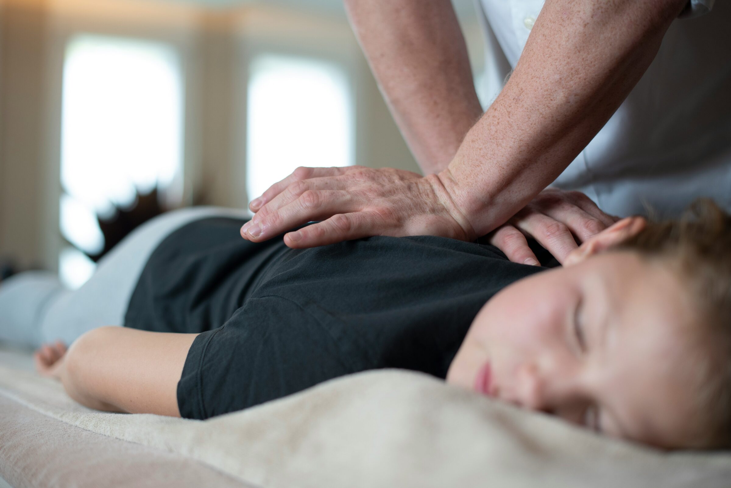 Close-up of hands on a child's back during a chiropractic adjustment
